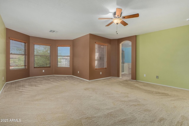 spare room with arched walkways, ceiling fan, carpet floors, and visible vents