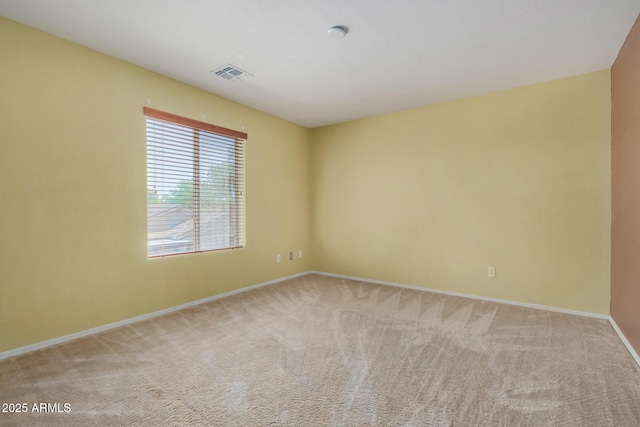 carpeted spare room featuring baseboards and visible vents
