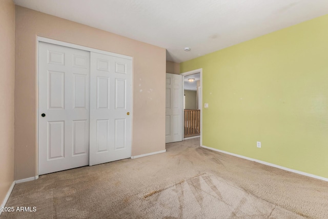 unfurnished bedroom featuring baseboards, carpet, and a closet