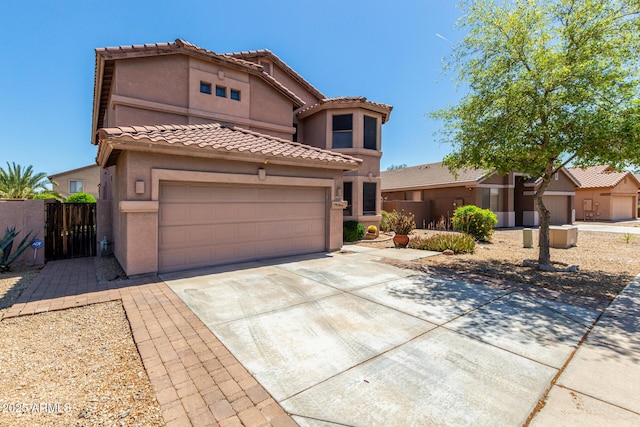 view of front of house featuring driveway, a tile roof, fence, an attached garage, and stucco siding