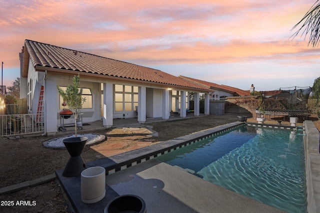 pool at dusk featuring a patio area