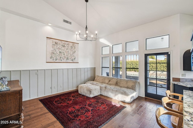 living room with dark hardwood / wood-style floors, a chandelier, and high vaulted ceiling