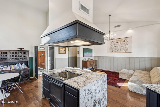 kitchen with light stone counters, dark hardwood / wood-style flooring, hanging light fixtures, and electric range oven