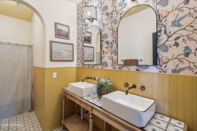 bathroom with dual sinks and wooden walls