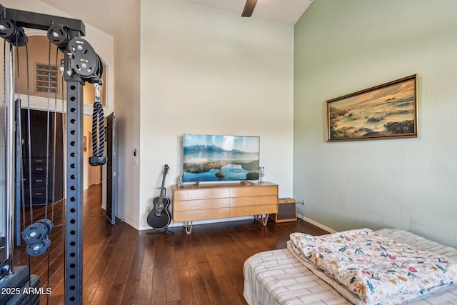 bedroom featuring hardwood / wood-style flooring, a high ceiling, and baseboards