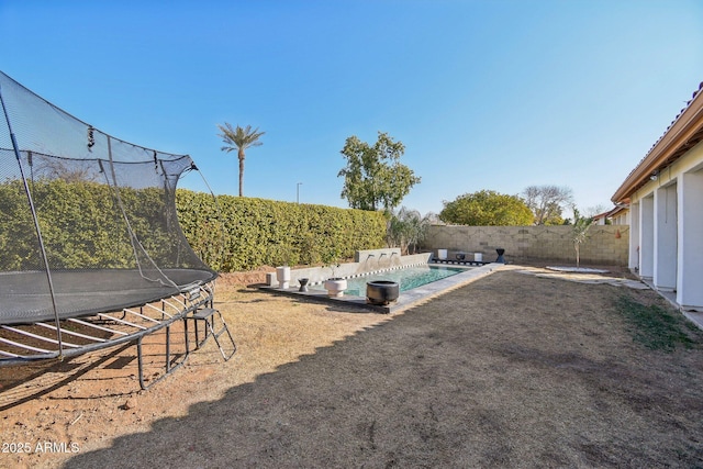 view of yard with a fenced in pool and a trampoline