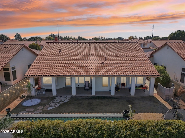 back house at dusk with a yard and a patio area