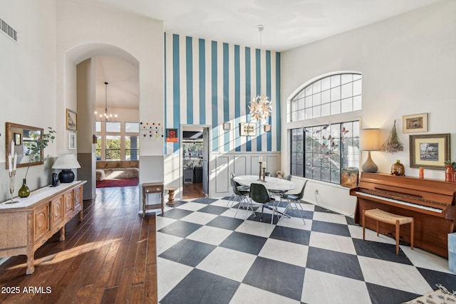 interior space featuring arched walkways, a high ceiling, dark wood-type flooring, and a notable chandelier