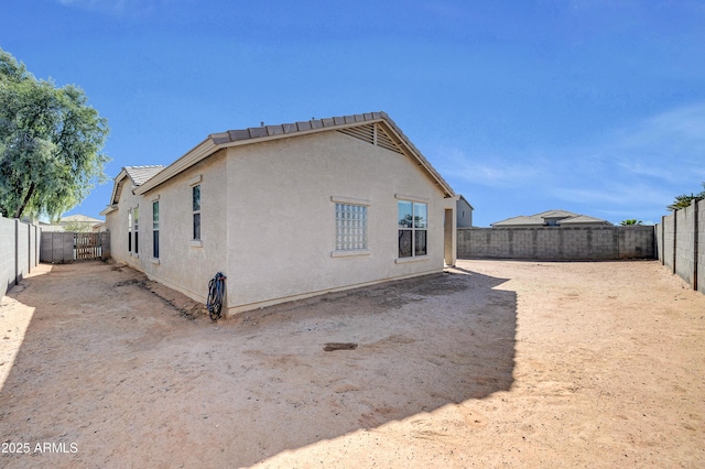 back of house featuring a fenced backyard and stucco siding