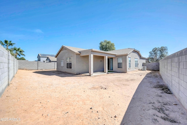 rear view of property featuring central air condition unit, a fenced backyard, and stucco siding