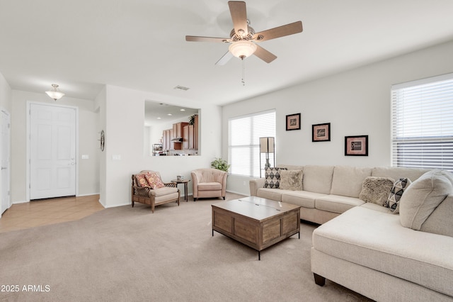 living area featuring visible vents, a ceiling fan, light carpet, light tile patterned flooring, and baseboards