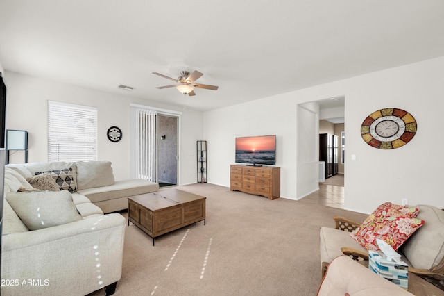 living area with carpet floors, visible vents, and a ceiling fan