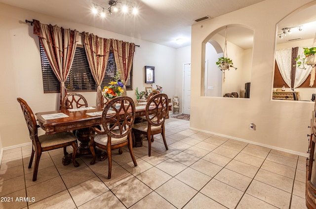 dining space with track lighting and light tile patterned floors