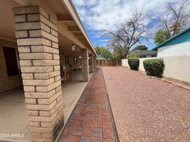 view of property exterior featuring a patio area, a fenced backyard, and brick siding