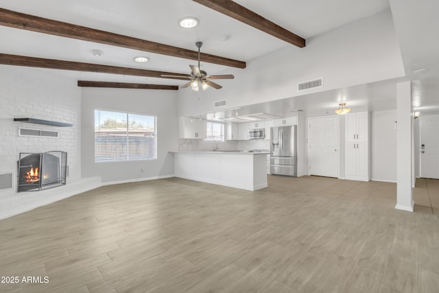 unfurnished living room with a brick fireplace, light wood-style floors, visible vents, and ceiling fan