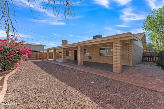 rear view of property featuring a patio, central AC unit, a fenced backyard, and brick siding