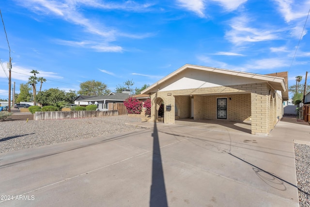 view of front of house with a carport, concrete driveway, brick siding, and fence