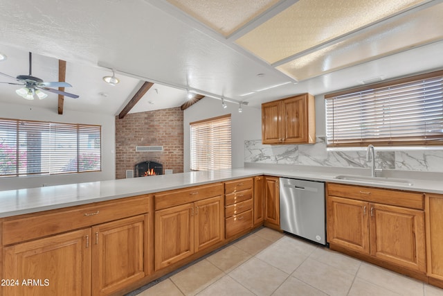 kitchen featuring backsplash, a brick fireplace, dishwasher, a peninsula, and a sink