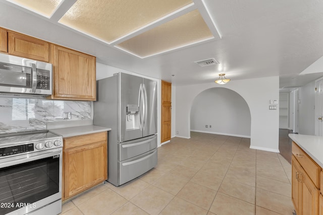 kitchen featuring backsplash, light tile patterned floors, and appliances with stainless steel finishes