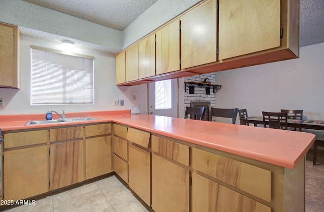 kitchen featuring a fireplace, a textured ceiling, light countertops, and a sink