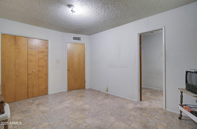 unfurnished bedroom with a closet, visible vents, a textured ceiling, and baseboards