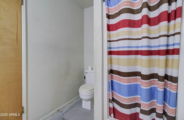 full bathroom with a textured ceiling, curtained shower, toilet, and baseboards