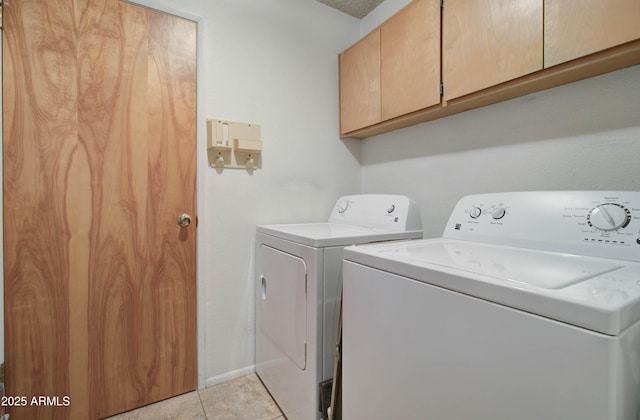 laundry room featuring light tile patterned floors, cabinet space, and washer and clothes dryer