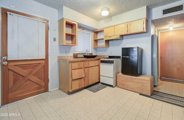 kitchen featuring open shelves, white gas stove, visible vents, a textured ceiling, and freestanding refrigerator