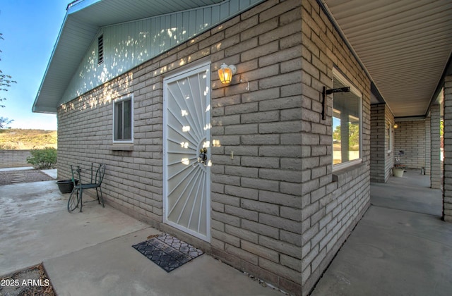 view of property exterior with a patio and brick siding