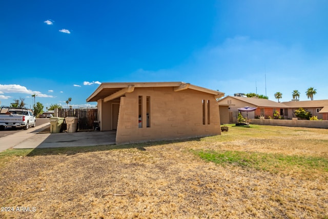 view of property exterior featuring a yard, fence, and stucco siding