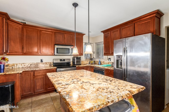 kitchen with light tile patterned floors, a kitchen island, appliances with stainless steel finishes, light stone countertops, and decorative light fixtures