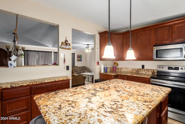 kitchen with light stone countertops, a kitchen island, appliances with stainless steel finishes, and pendant lighting