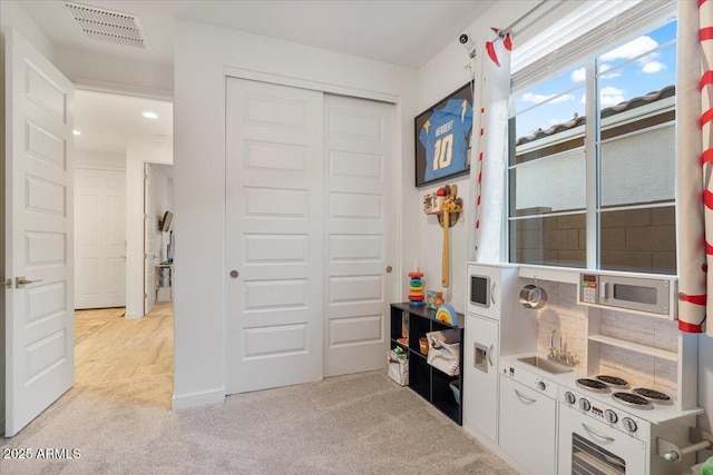 rec room featuring visible vents, light carpet, and a sink