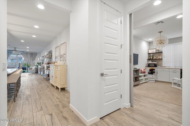 hall with a notable chandelier, visible vents, recessed lighting, and light wood-style floors