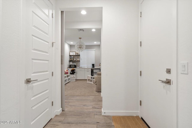 hallway featuring baseboards, recessed lighting, and light wood-type flooring