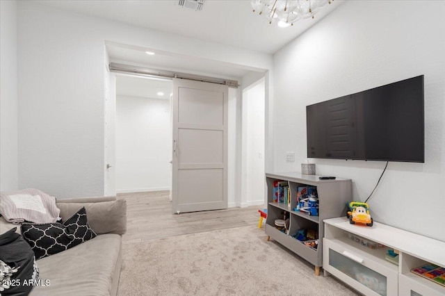 living room with a barn door, wood finished floors, baseboards, visible vents, and recessed lighting