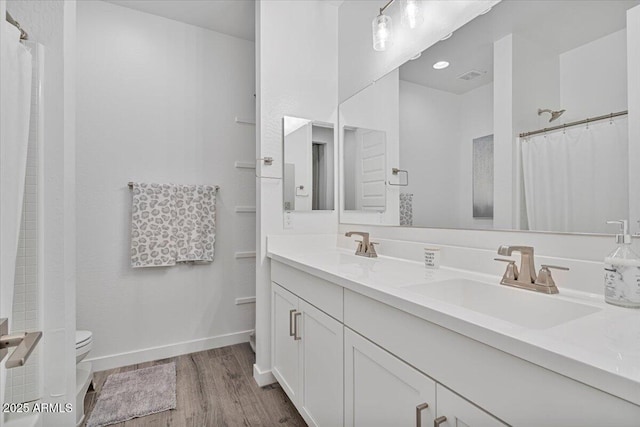 full bathroom featuring a shower with curtain, wood finished floors, double vanity, and a sink