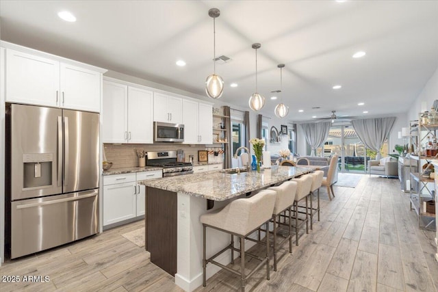 kitchen with light wood-style flooring, a sink, visible vents, white cabinetry, and appliances with stainless steel finishes
