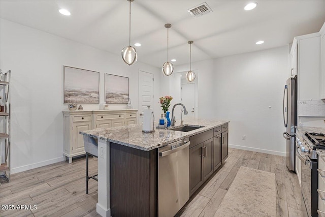 kitchen featuring light wood-type flooring, stainless steel appliances, visible vents, and a sink