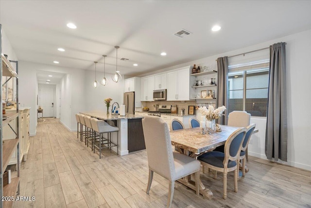 dining area with baseboards, light wood-style flooring, visible vents, and recessed lighting