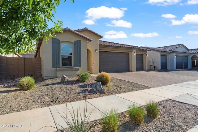view of front of property featuring a tiled roof, driveway, fence, an attached garage, and stucco siding