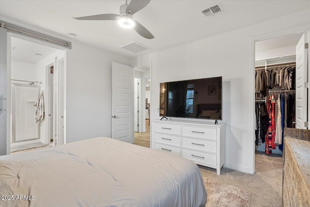 bedroom featuring a walk in closet, a closet, visible vents, and light colored carpet