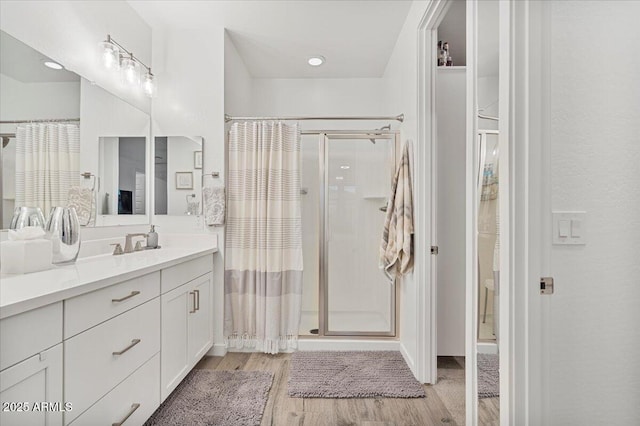 bathroom with a shower stall, vanity, and wood finished floors