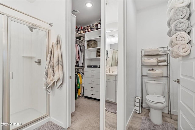 full bathroom featuring a shower stall, visible vents, toilet, vanity, and a walk in closet