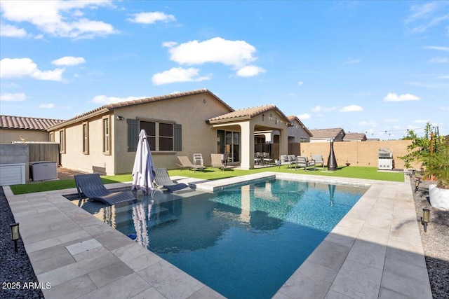 back of property featuring a tile roof, a fenced backyard, a patio, a fenced in pool, and stucco siding