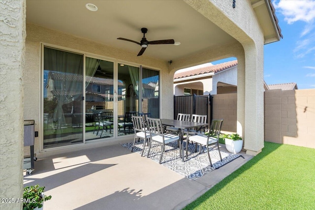 view of patio with outdoor dining area, fence, and a ceiling fan