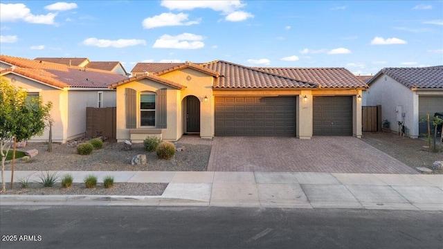 mediterranean / spanish home featuring stucco siding, a tile roof, driveway, and a garage