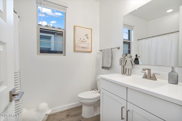 full bath with wood finished floors, vanity, toilet, and baseboards