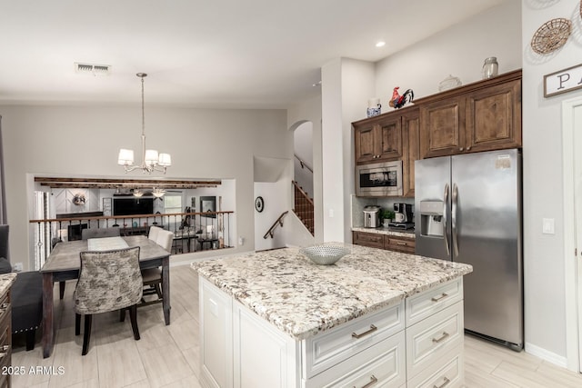 42711 N 45th Dr, Phoenix, AZ 85087 - kitchen with visible vents, open floor plan, light stone counters, arched walkways, and appliances with stainless steel finishes