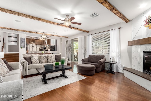 42711 N 45th Dr, Phoenix, AZ 85087 - living room with a premium fireplace, a ceiling fan, wood finished floors, beamed ceiling, and visible vents